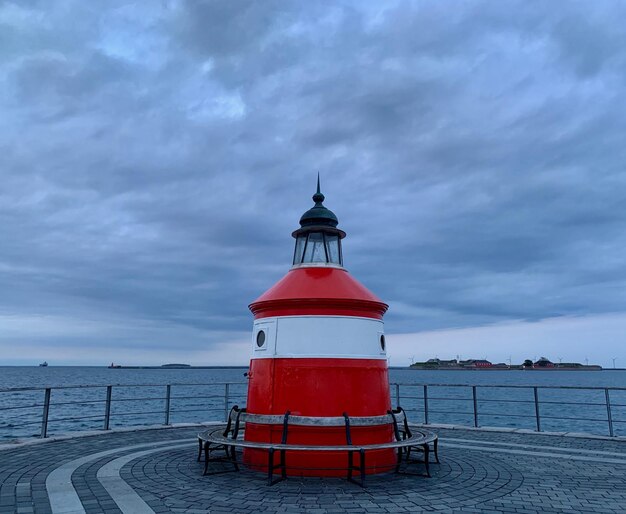 Red lighthouse by sea against sky