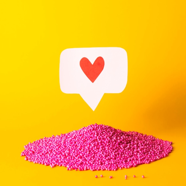 Photo red like heart icon on a pink pin over pink balls many emoji hearts in social networks concept