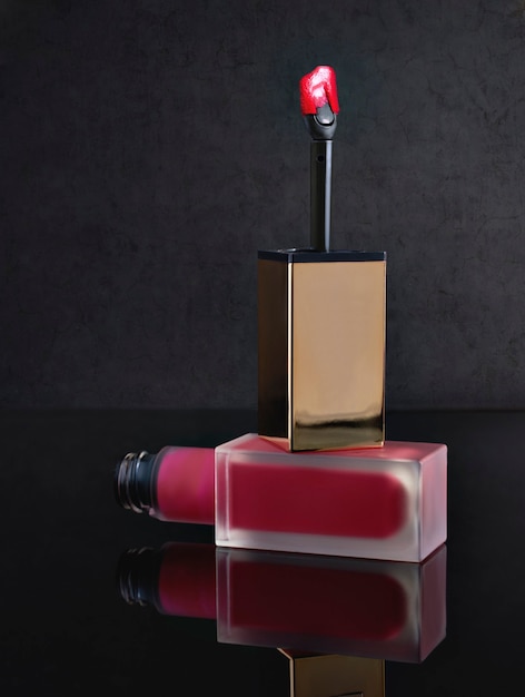 Red lip gloss on a black backgroundwith a brush for applying makeup