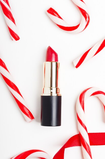 Red lipstick and candy canes top view composition.