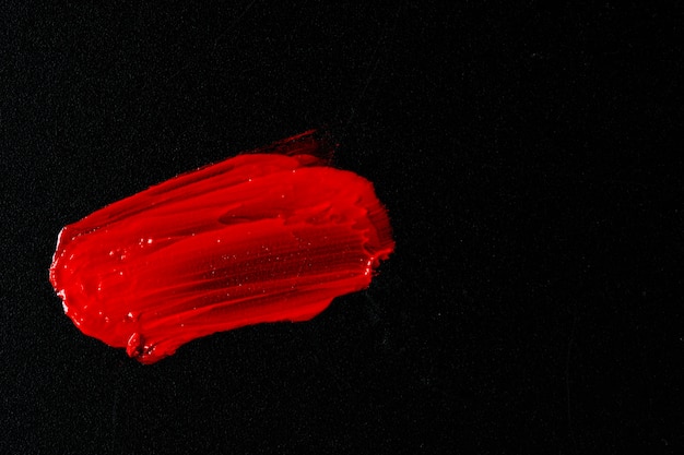 Red lipstick on dark paper background close up