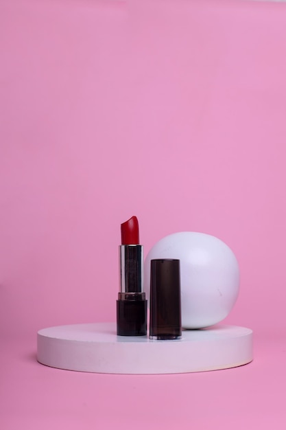 Foto rossetto rosso sul podio su sfondo rosa.