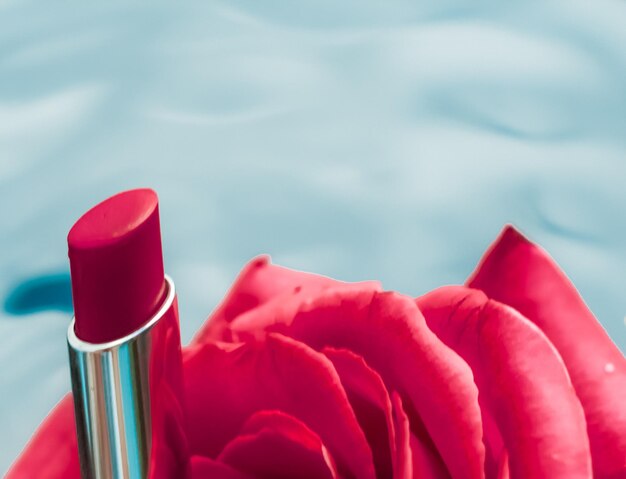 Red lipstick and rose flower on liquid background waterproof glamour makeup and lip gloss cosmetics product for luxury beauty brand holiday design