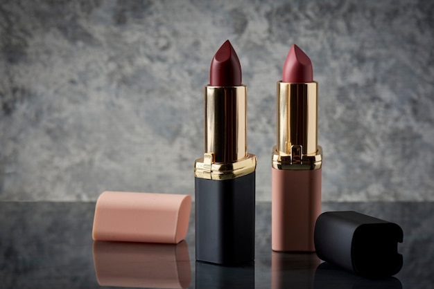Red lipstick with black and pink on a marble surface with the lids thrown to the side