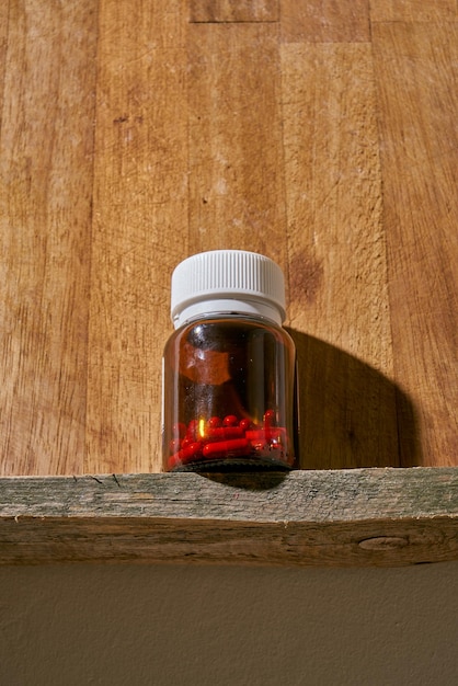 Красные таблетки лития в бутылочке с лекарством на деревянной полке.