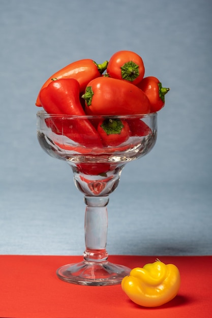 Red little sweet pepper in a glass vase on a red background.