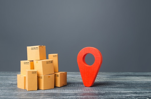 Red location pointer geolocation symbol and cardboard boxes