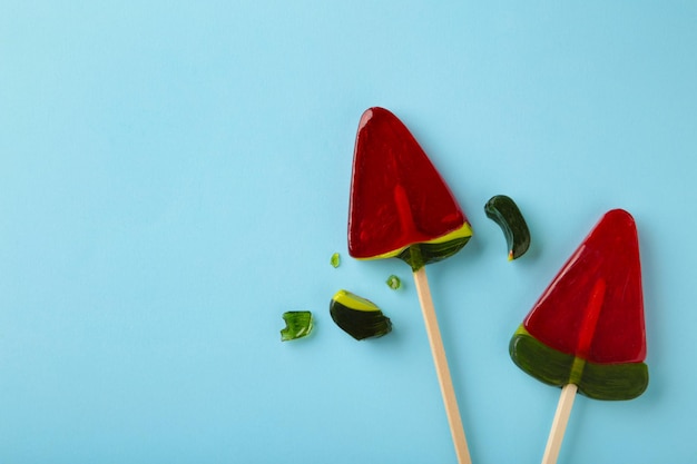 Red lollipop candy broken in pieces on blue background. Top view