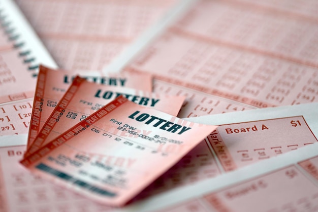 Red lottery ticket lies on pink gambling sheets with numbers for marking to play lottery Lottery playing concept or gambling addiction Close up