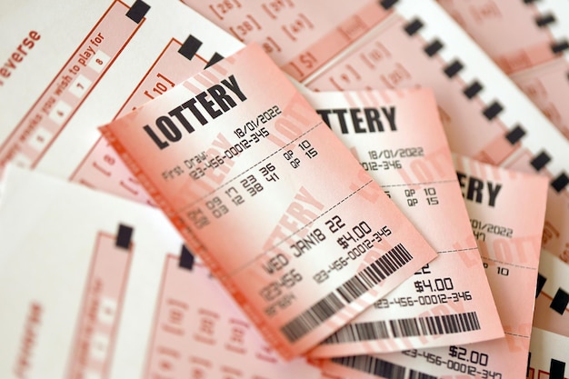 Red lottery ticket lies on pink gambling sheets with numbers for marking to play lottery Lottery playing concept or gambling addiction Close up