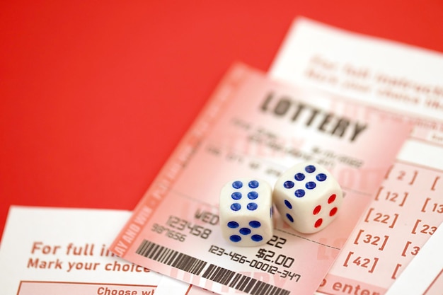 Красный лотерейный билет с игральными костями лежит на розовых игровых листах с номерами для маркировки для игры в лотерею. Концепция игры в лотерею или зависимость от азартных игр.
