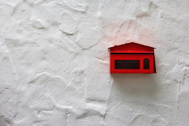 red mailbox on white concrete wall