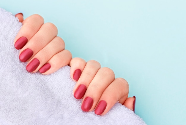 Red manicure on white towel, copy space