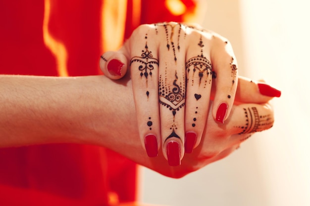 Red manicured hands with Mehndi