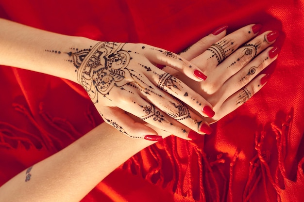 Red manicured hands with Mehndi