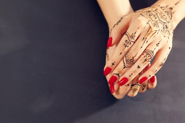 Photo red manicured hands with mehndi