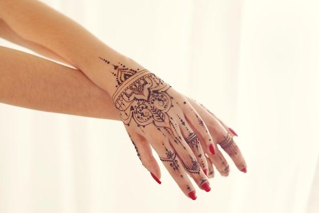 Red manicured hands with Mehndi