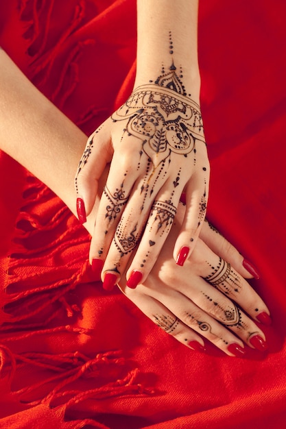 Red manicured hands with Mehndi 