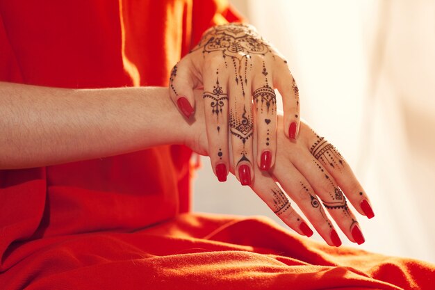 Red manicured hands with Mehndi 