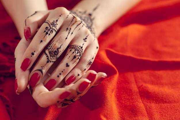 Red manicured hands with Mehndi