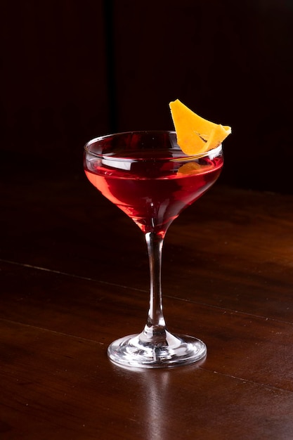 Красный напиток мартини со стеклом и апельсиновой цедрой, вид под углом