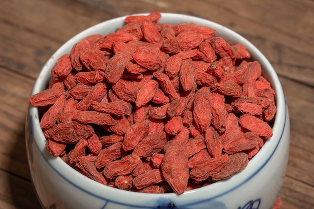 The red medlar is in a plate or bowl on a wooden table.