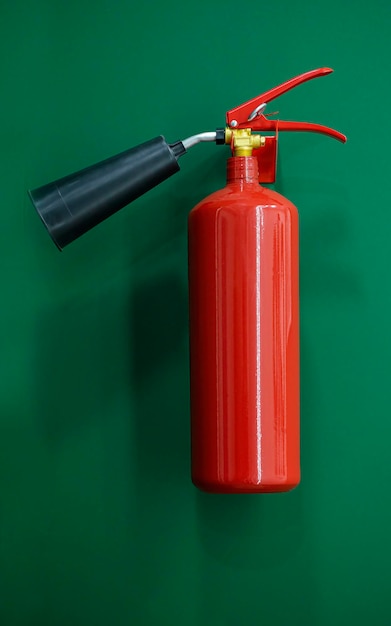 Photo red metal extinguisher on the green wall in corridor of the modern office