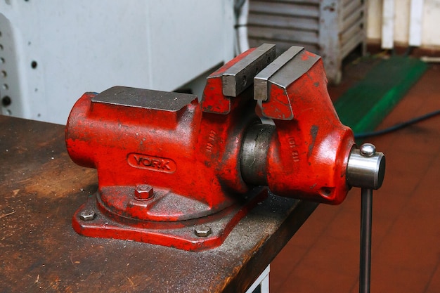 Photo red metal vice on wooden table on factory