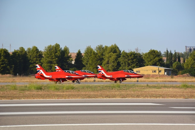 Red Military fighter planes stand on the runway in a column