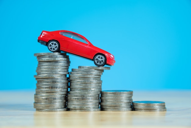 red miniature car model on stack of coins