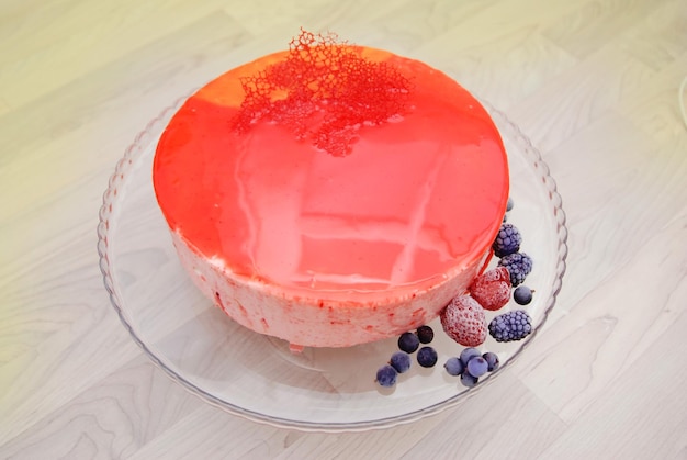 Torta mousse alla frutta glassata a specchio rosso senza decorazione. vista dall'alto. frutti di bosco ghiacciati.