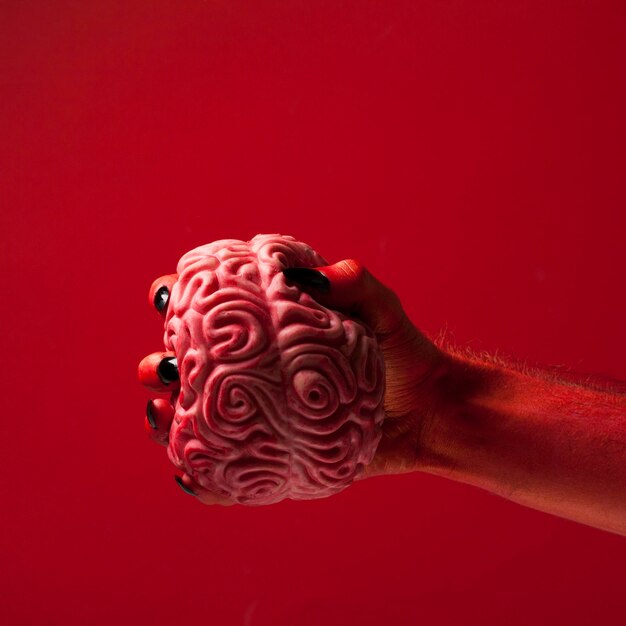 Red monster devil hand holing a human brain