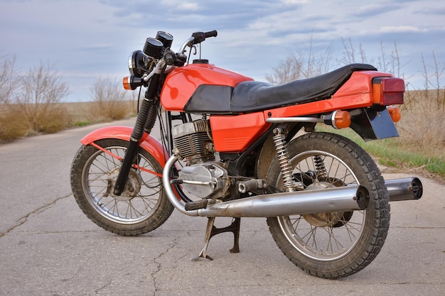 Foto la motocicletta rossa si erge sulla bici vintage da strada vuota