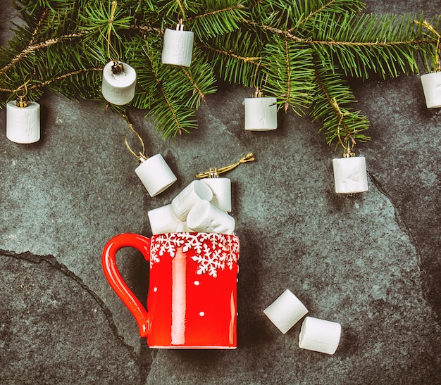 Red mug and Christmas tree branch with marshmallow. 