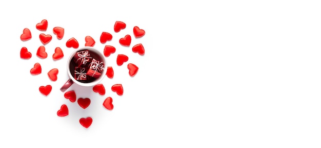 Красная кружка с подарками стоит в сердцах на белом. Концепция Дня святого Валентина