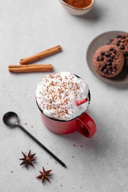 Красная чашка с горячим шоколадом или какао с битым сливочным печенье ложкой корицы и звездным анисом