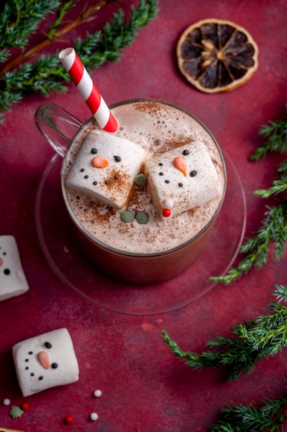 Red mug with hot chocolate and melted marshmallow snowman red festive background