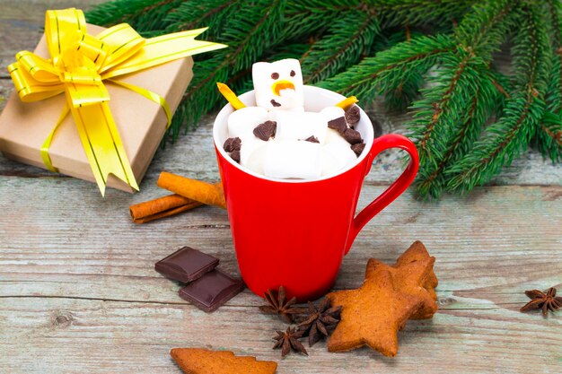 Red mug with hot chocolate with melted marshmallow snowman.