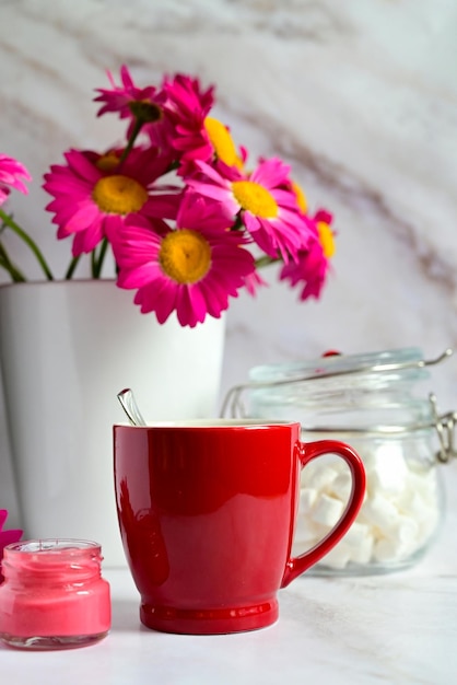赤い花の花束の背景にお茶と赤いマグカップ