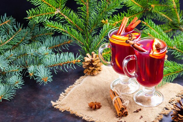 Red mulled wine and fir branches on burlap Mulled wine with oranges honey cinnamon and cloves