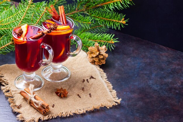 Red mulled wine and fir branches on burlap Mulled wine with oranges honey cinnamon and cloves