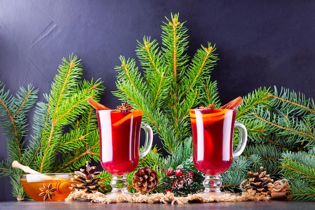 Red mulled wine and fir branches on burlap Mulled wine with oranges honey cinnamon and cloves