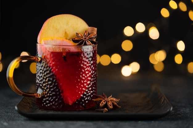 Red mulled wine with spices orange and apple on dark background Copy space