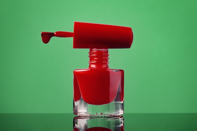 Red nail polish bottle on green background