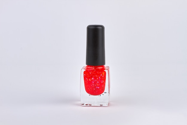 Red nail polish bottle isolated on white. Nail varnish close up.