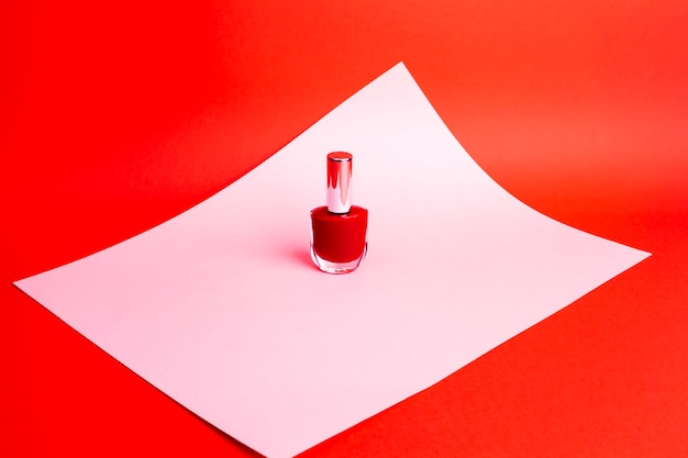 Красный лак для ногтей на красном фоне с копировальным пространством
