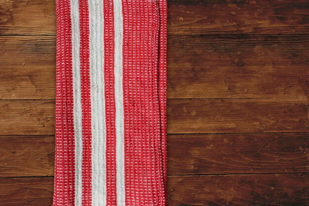 Red napkin with white stripes over wooden table top view background