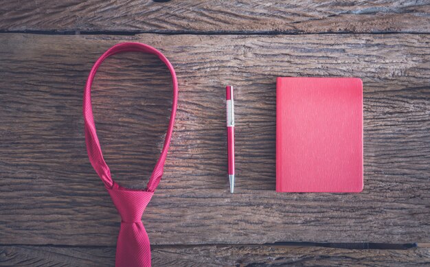 Red necktie, pen, note book on wooden table