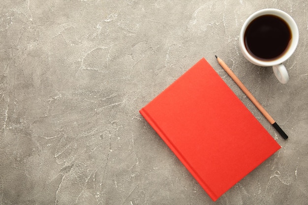 Photo red notebook with coffee cup and pencil on grey background. flat lay, creative workspace office. business-education concept with copy space.