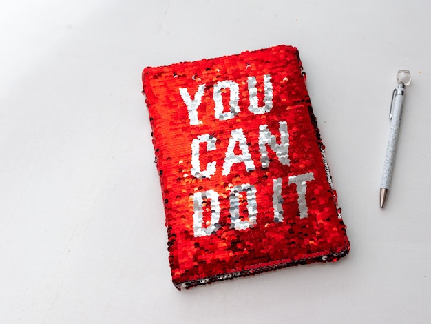 A red notebook with the inscription-you can do it